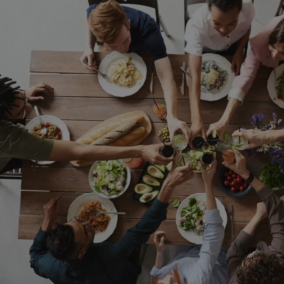 people gathering around a table making a cheers gesture