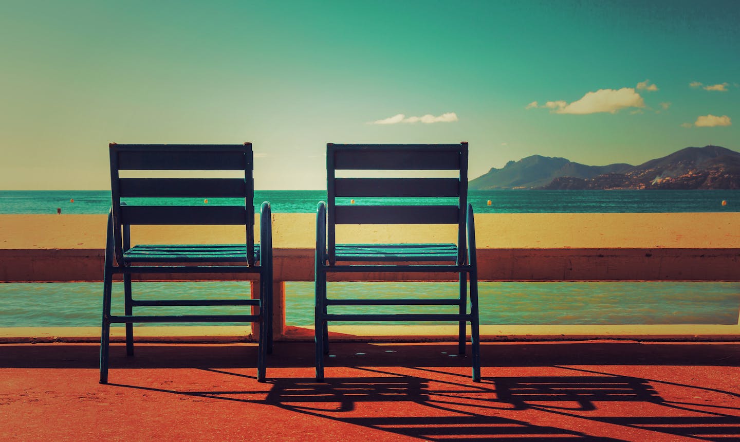 two chairs overlooking sea with mountains in distance
